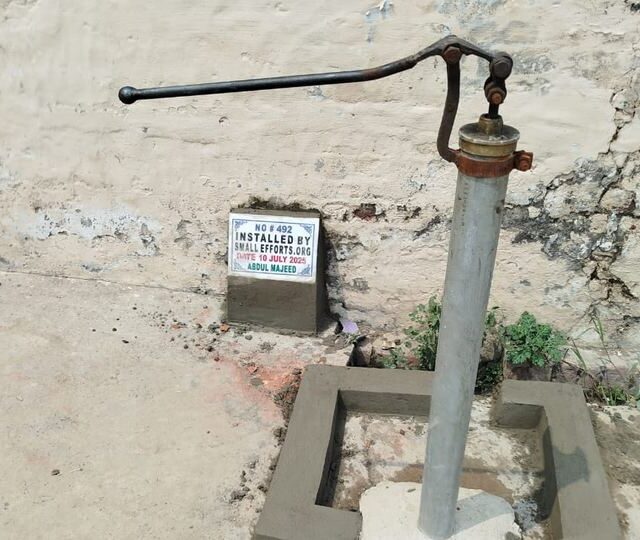 A finished hand pump on its concrete apron